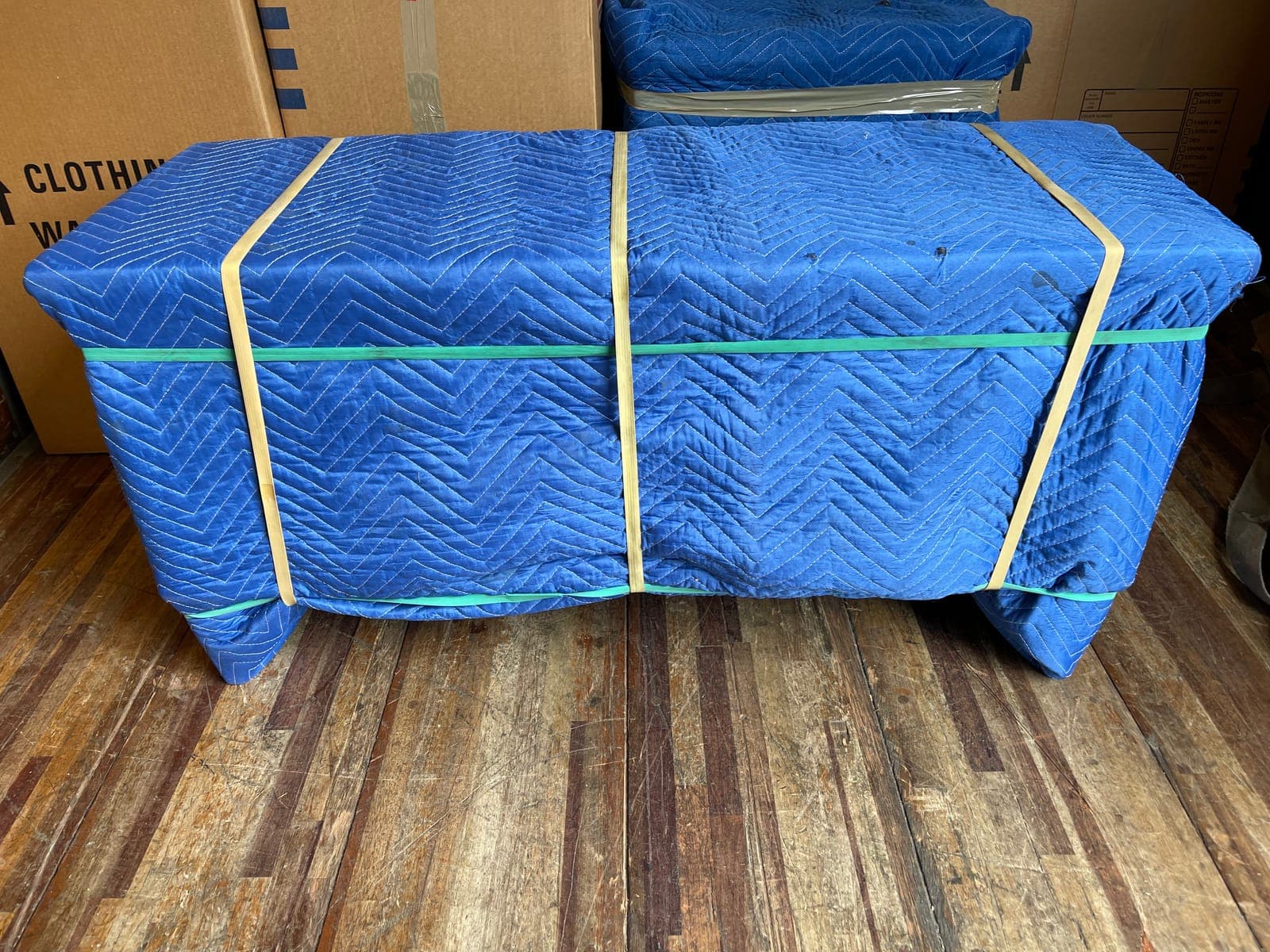 A dresser fully blanket wrapped and banded, standing in the back of a loaded trailer